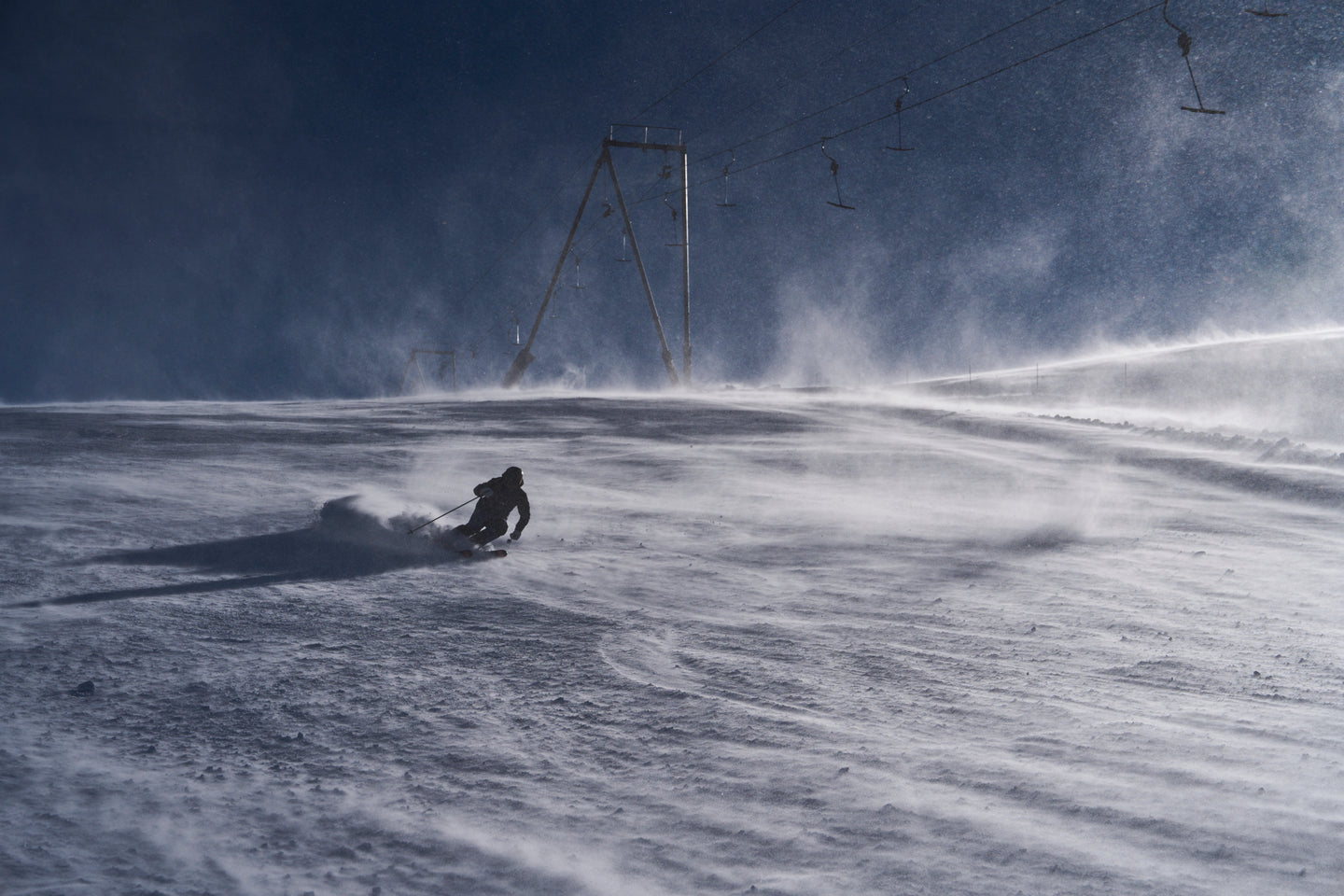 Skier carving in windy alpine conditions