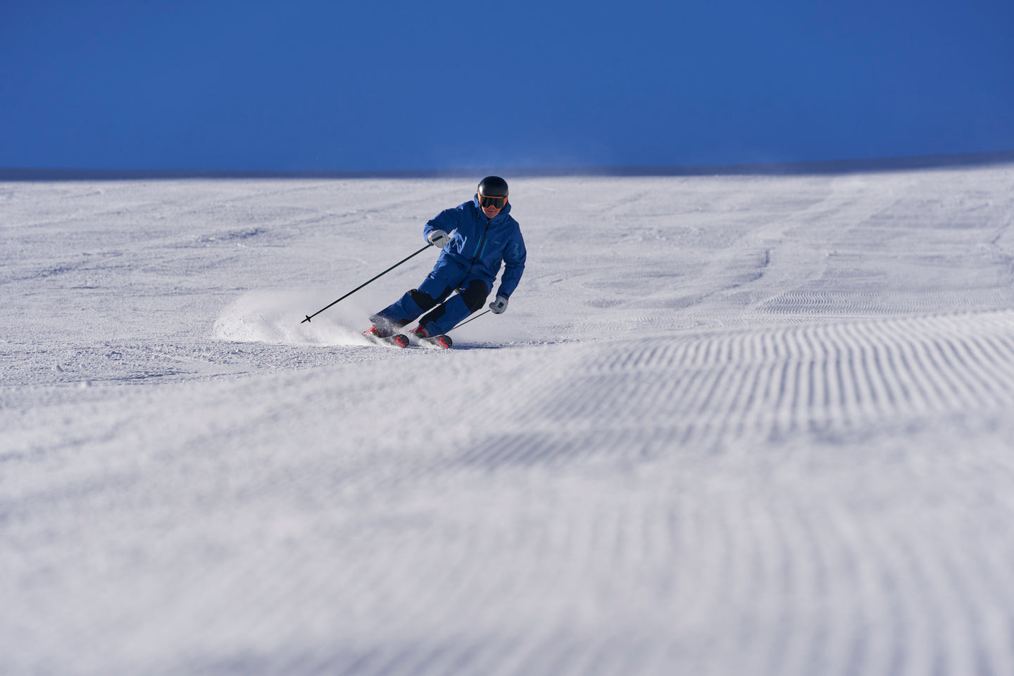 Alpine skier carving on groomed piste