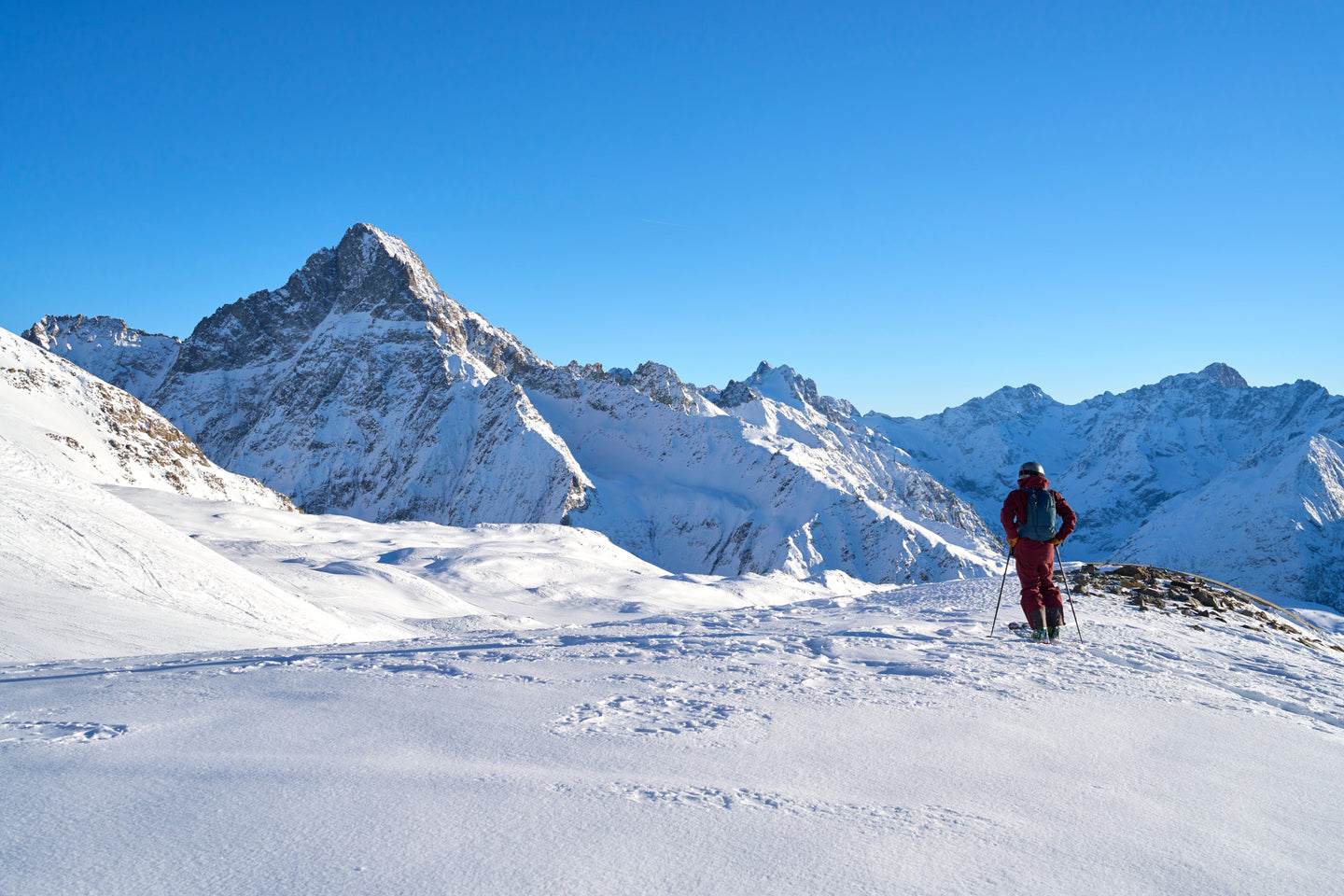 Skier looking out across a snowy mountain landscape on a clear day